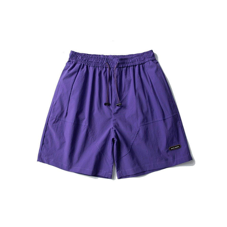 Purple drawstring shorts with elastic waist, curved front seams and a small oval label, flat front view