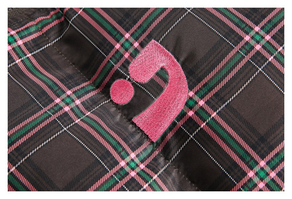 Close-up of a small pink embroidered mark on the dark plaid jacket.