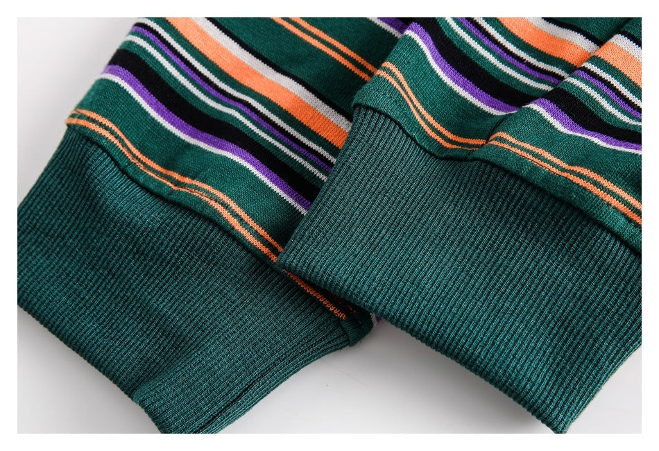 Close-up of two ribbed dark green garment cuffs with orange, purple, white, and black stripes.