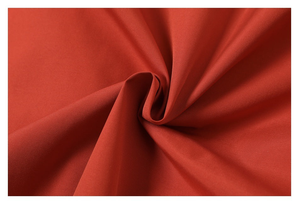 Rust-red fabric gathered into folds, showing its surface and drape.