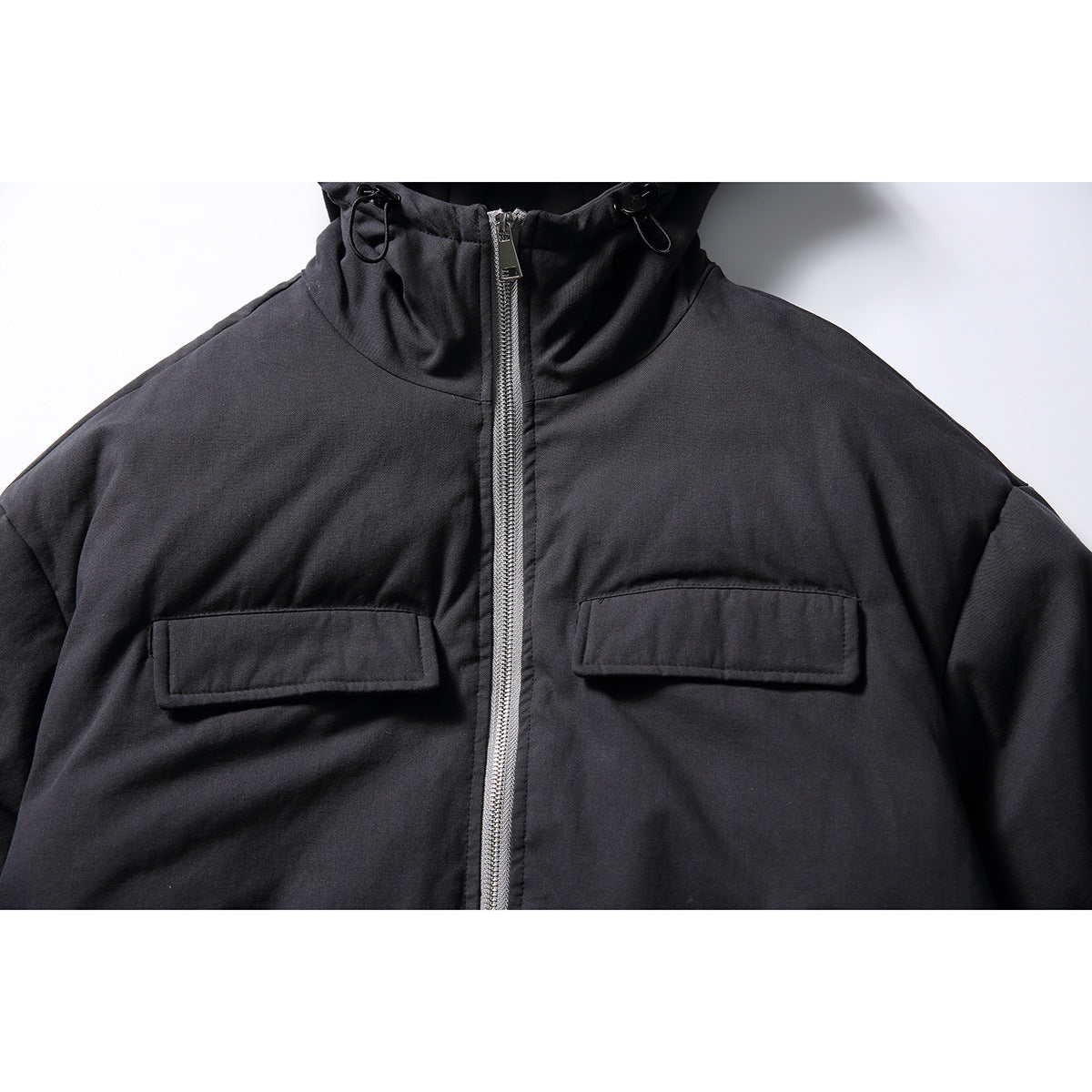 Close-up of the black jacket's hood, silver zipper, and two flap chest pockets.