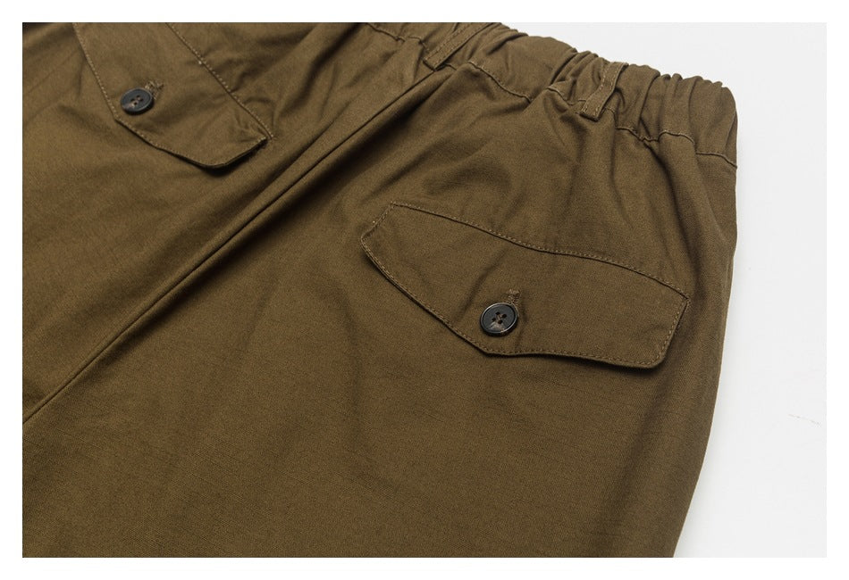 Close-up of the back of brown pants, highlighting a button-flap pocket and elastic waistband.