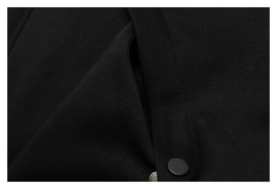 Close-up of a black garment's snap-button placket and stitched seam.