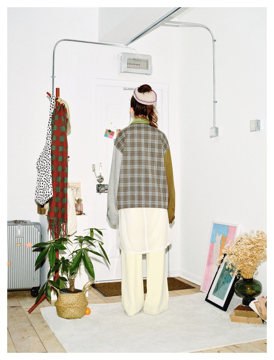 Back view of a model wearing a jacket with a gray-brown plaid back, green collar, and contrasting gray and olive sleeves.
