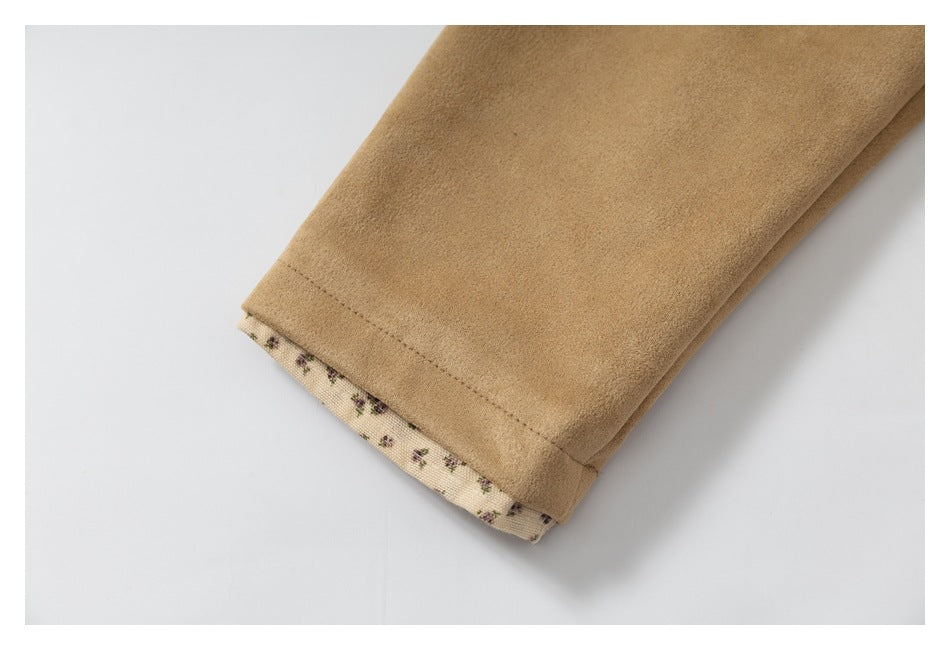 Close-up of a tan sleeve cuff with a narrow cream floral-print lining visible at the edge.