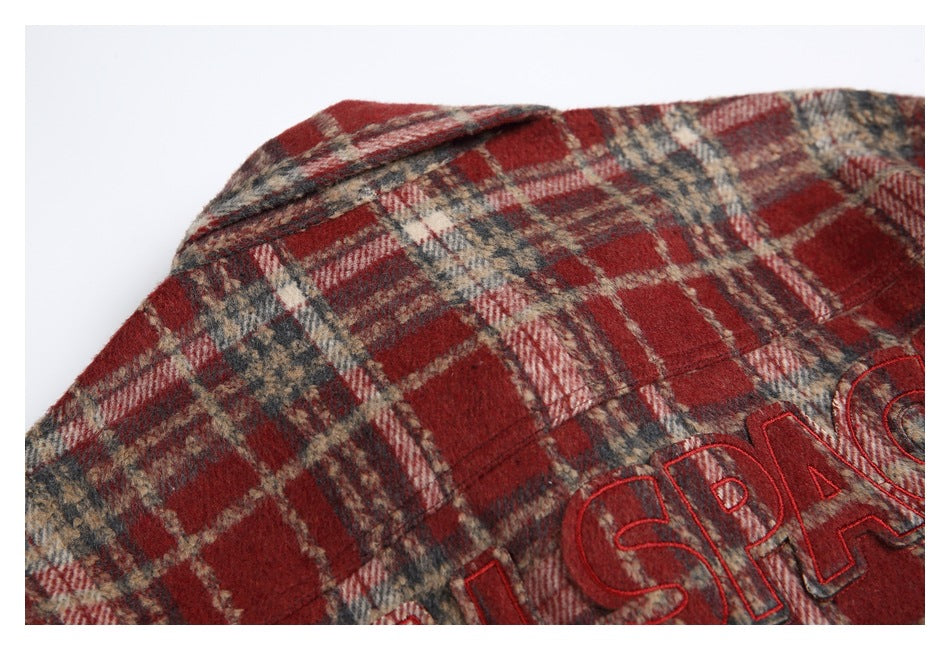 Close-up of the plaid shirt collar and partial red embroidered lettering.