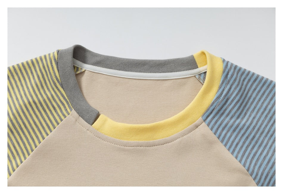 Close-up of a beige raglan T-shirt neckline with a yellow collar and contrasting striped sleeves.