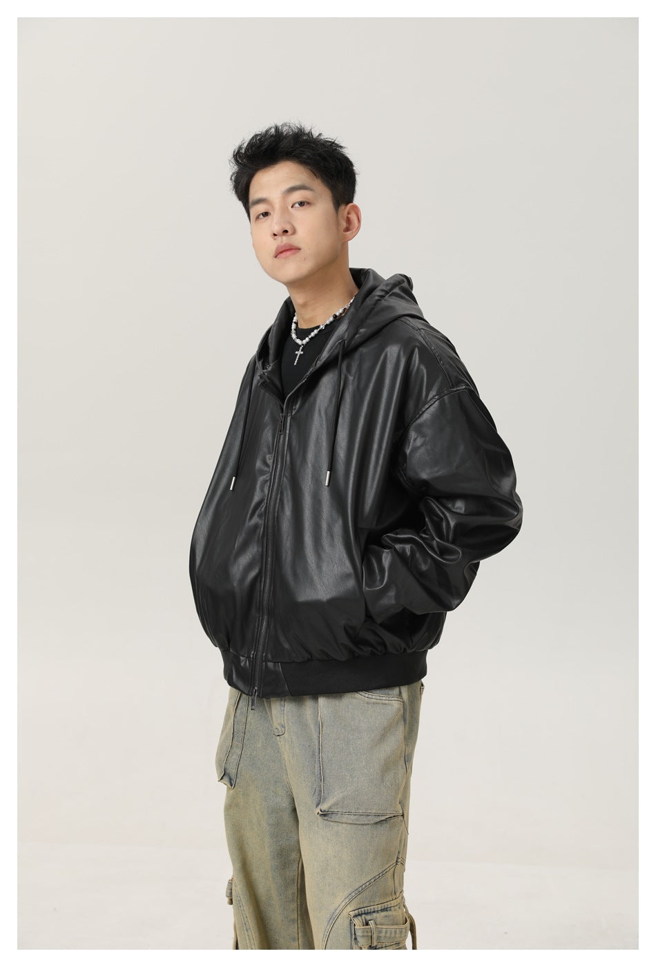 Angled view of a model wearing a black hooded zip jacket with a ribbed hem and faded cargo jeans.