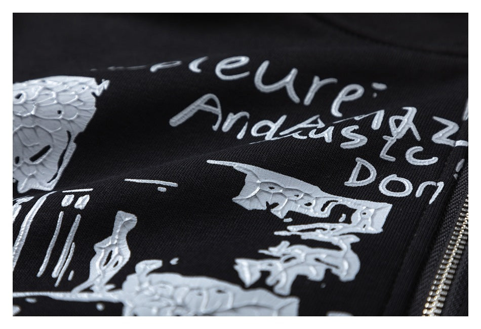 Close-up of raised silver lettering and illustrated graphics printed on the black hoodie.
