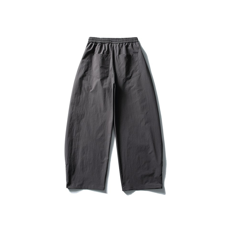 Back view of charcoal gray relaxed, wide-leg pants with an elastic waistband and two rear patch pockets.