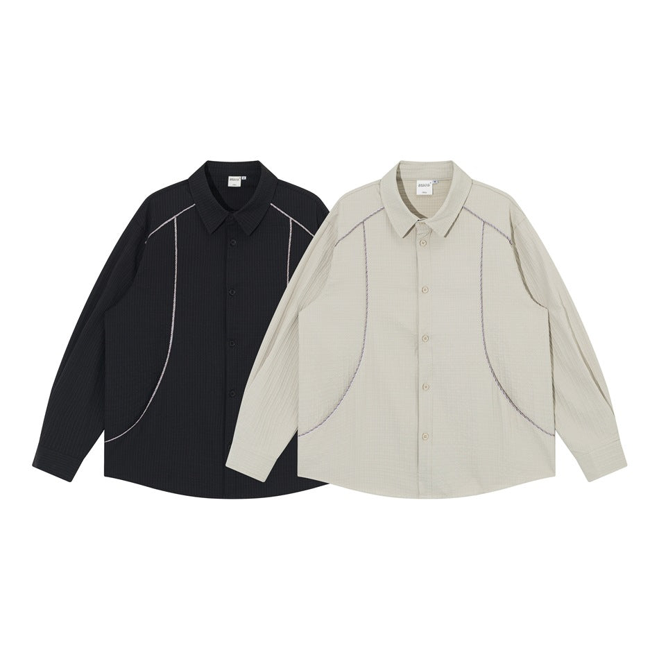Two long-sleeved collared shirts shown from the front: one black and one light beige, both with contrast piping.