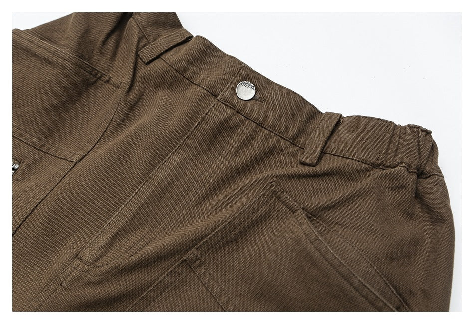 Close-up of brown trousers showing a buttoned waistband, belt loops, and a slanted pocket.