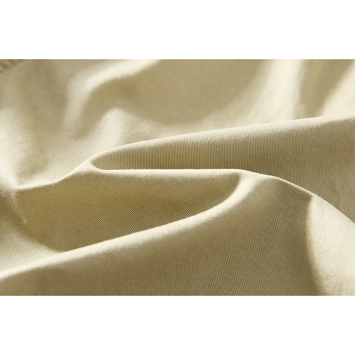 Macro view of the beige shorts fabric, showing its fine diagonal weave and folds.