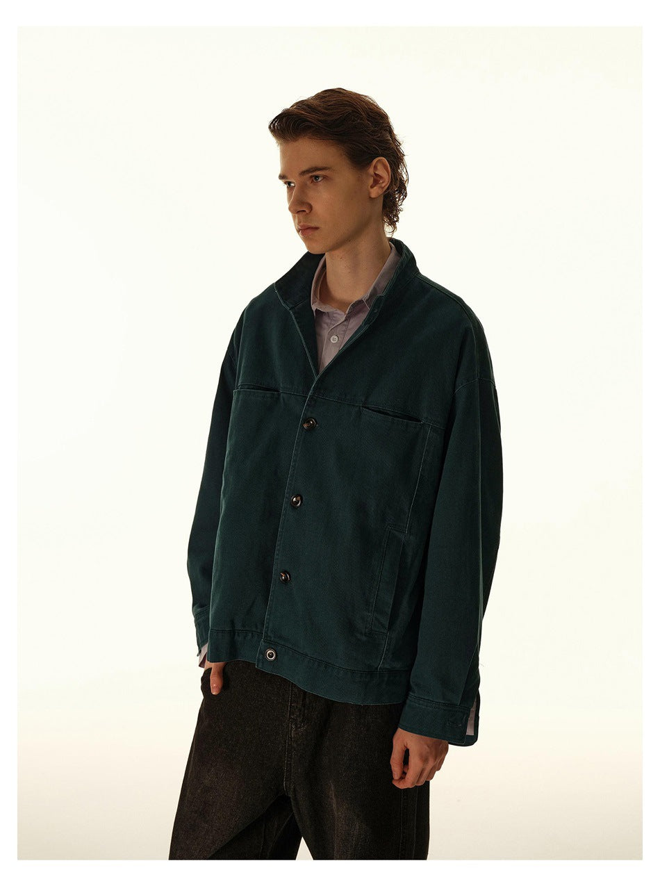 Three-quarter view of a model wearing an oversized dark teal button-front jacket with large pockets.