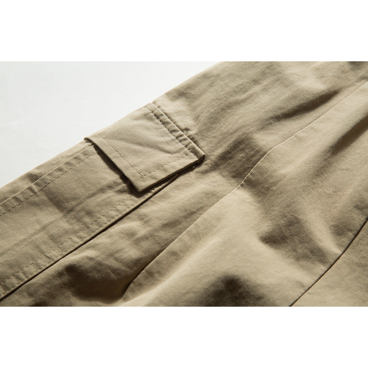 Close-up of khaki shorts showing a flap pocket and stitched seams.