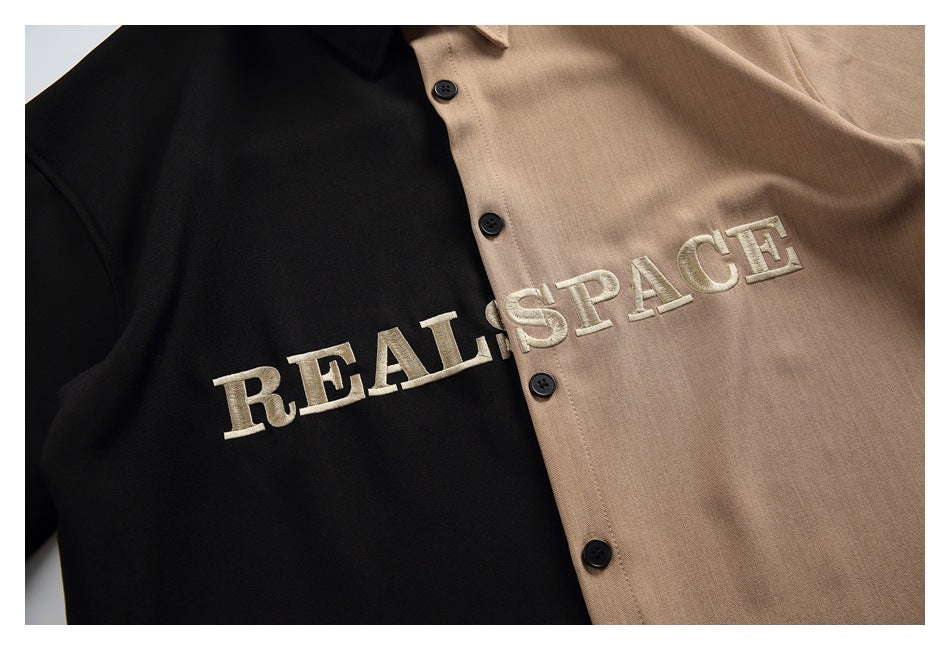 Close-up of cream REAL SPACE lettering embroidered across the black and tan shirt front beside its buttons.