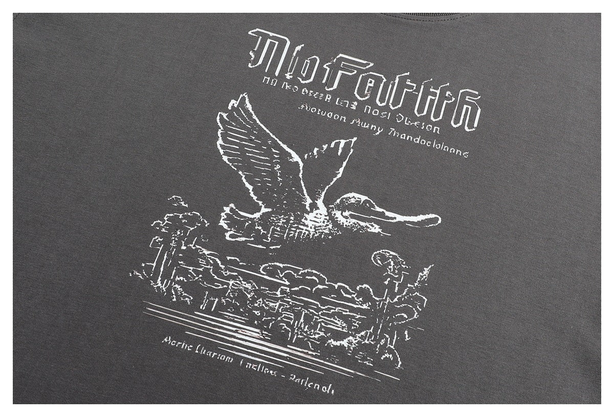 Close-up of the T-shirt's white graphic, featuring stylized lettering, a flying bird, and a landscape.