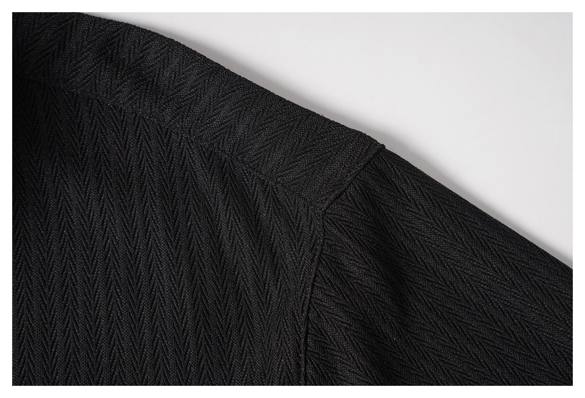 Close-up of the black shirt's shoulder seam and sleeve in a raised diagonal texture.