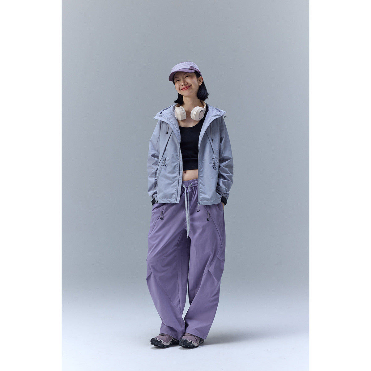 Woman wearing a light gray hooded jacket with lavender pants, shown from the front.
