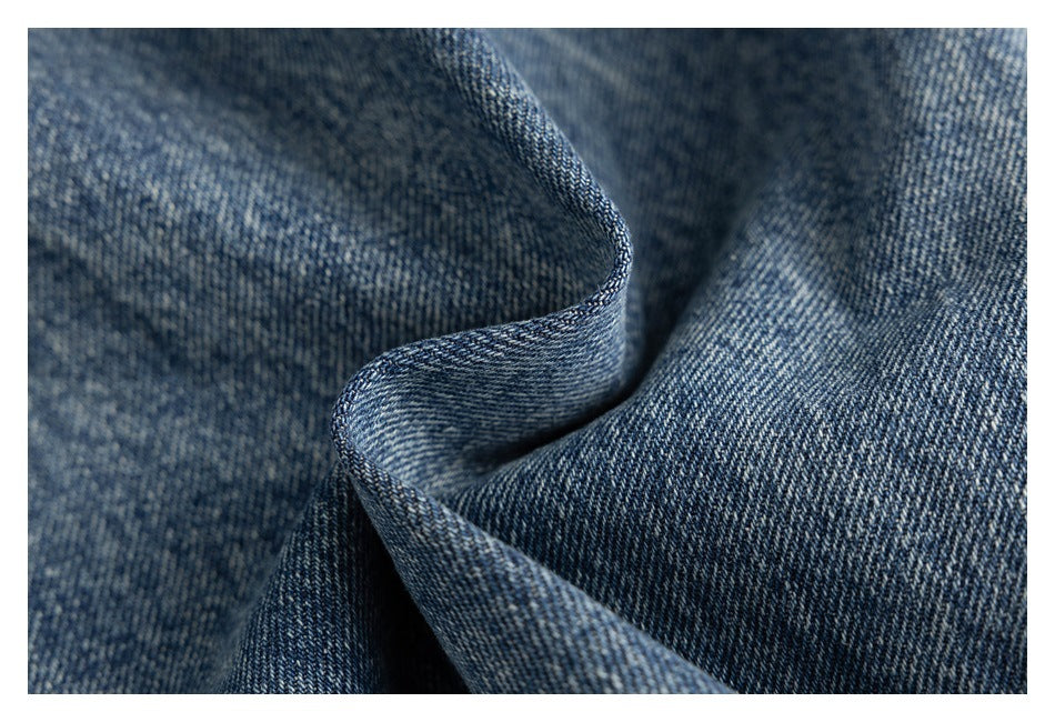 Close-up of textured blue denim fabric folded to show its weave and faded wash.
