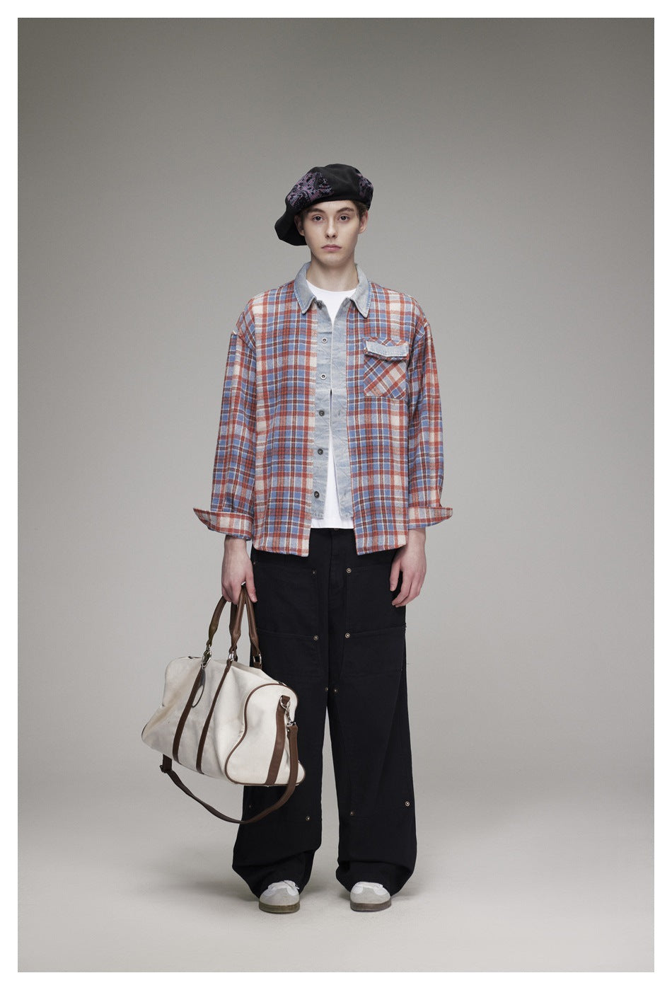 Front view of a model wearing a rust, blue and cream plaid button-up shirt with a light denim collar and chest pocket.