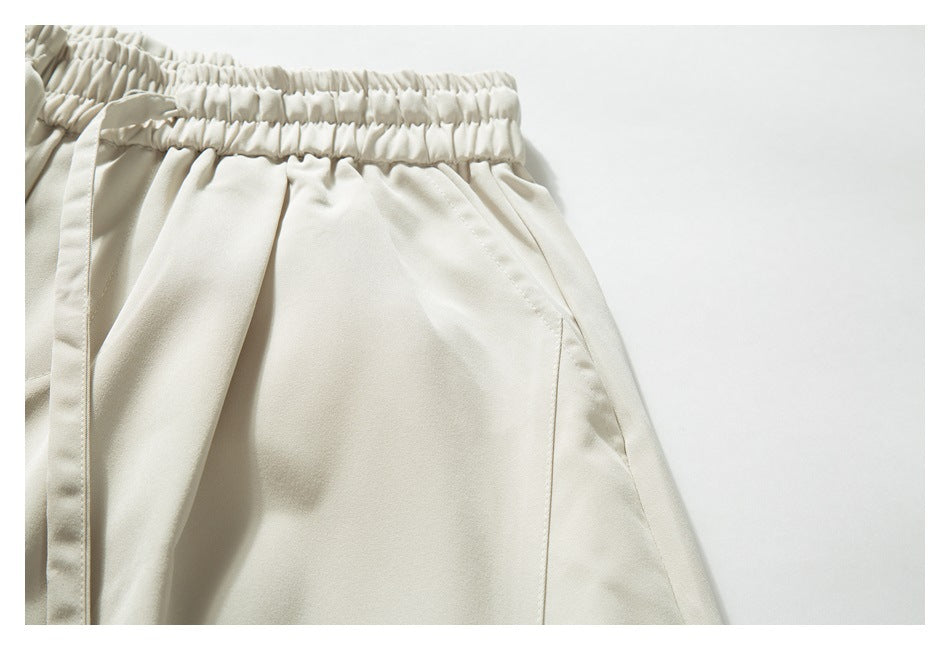 Close-up of ivory pants showing the elastic waistband and angled front pocket opening.