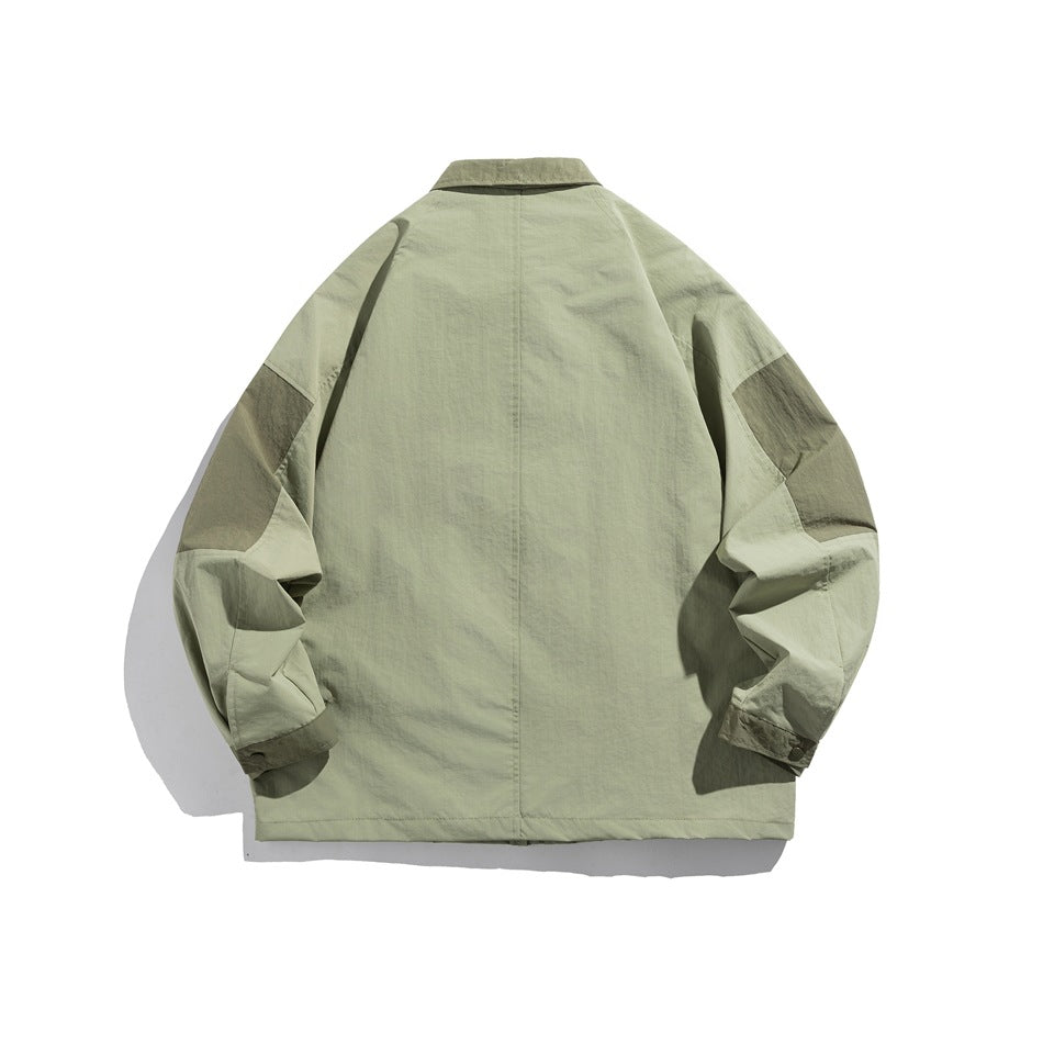 Back view of sage green jacket with center seam, darker contrast shoulder panels and snap cuffs