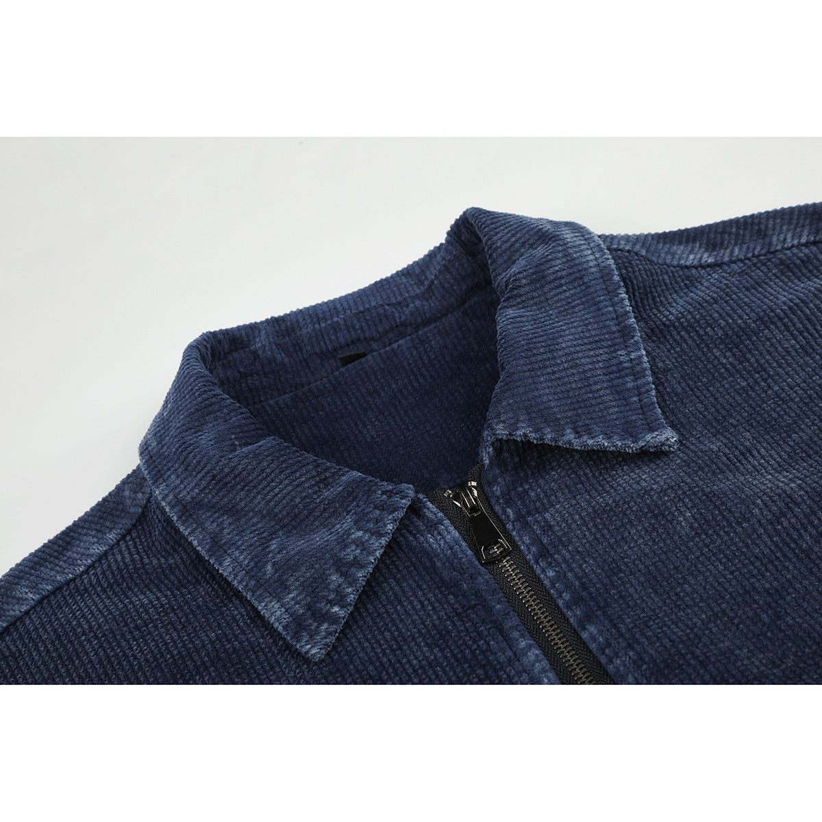 Close-up of a dark blue ribbed jacket collar and black front zipper.