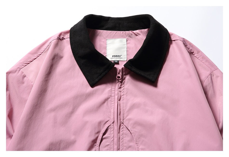 Close-up of a pink jacket front showing its black ribbed collar, zipper and sewn-in neck label.