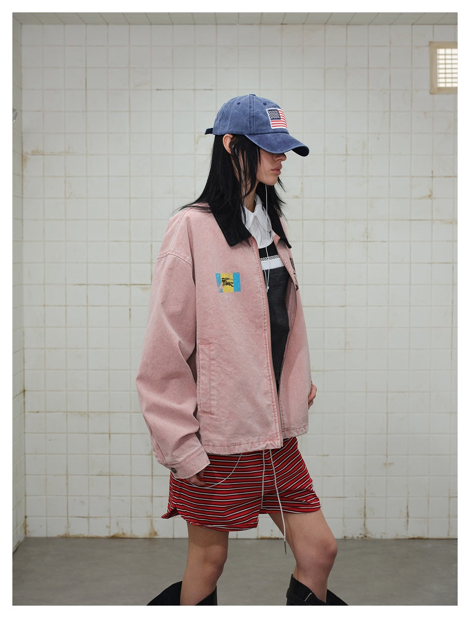 Side view of a model wearing a dusty pink jacket with a black collar and colorful chest patch.