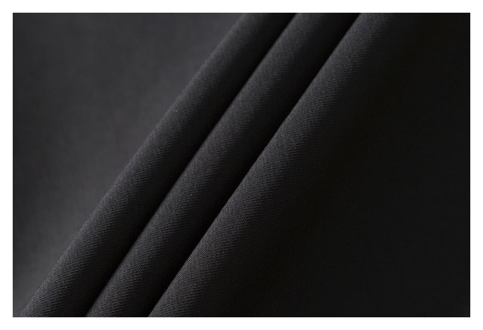 Close-up of black fabric draped in soft folds, showing its fine surface texture.