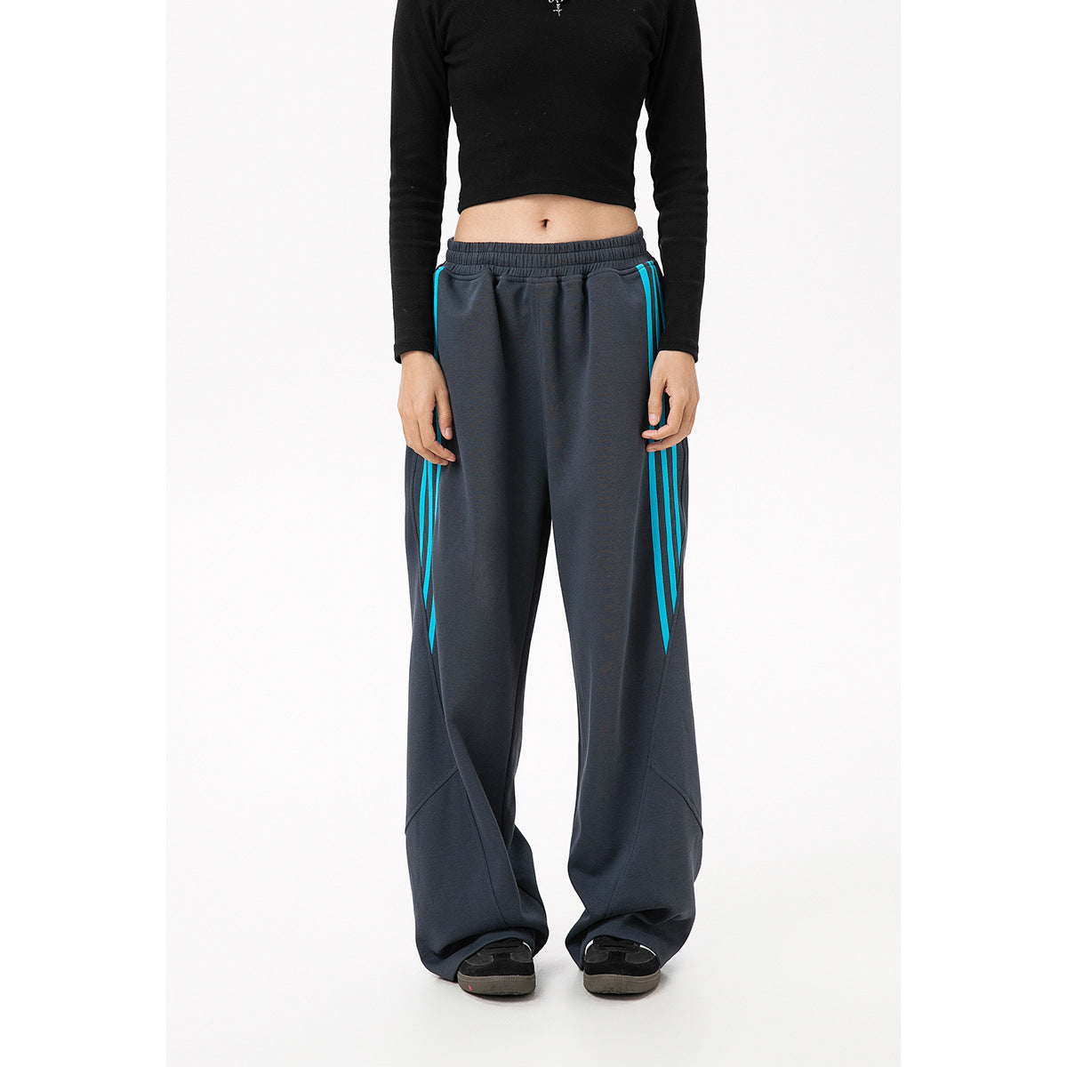 Front view of charcoal wide-leg track pants with an elastic waist and turquoise side stripes, worn by a model.