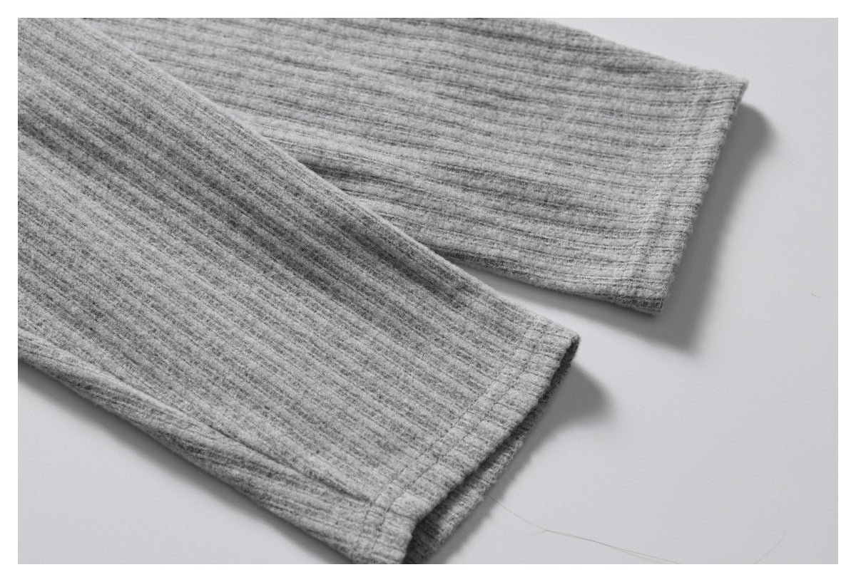 Close-up of two long sleeves and their stitched cuffs on a heather gray ribbed garment.