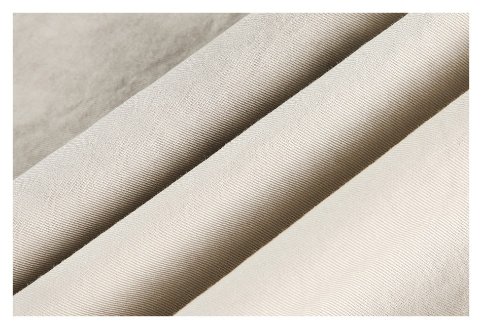 Close-up of folded light beige fabric showing its fine diagonal weave and tonal variation.