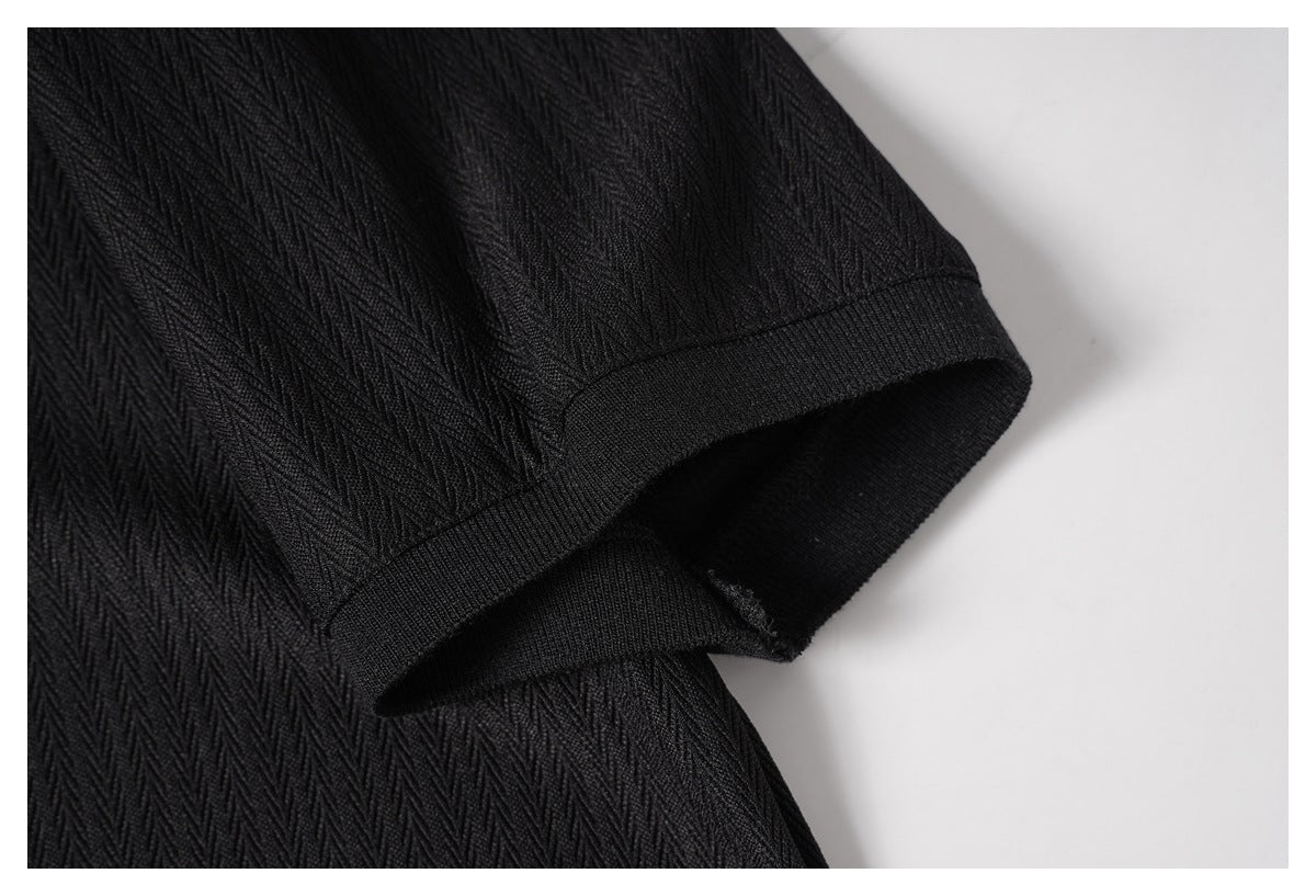 Close-up of a short sleeve and stitched cuff on a black textured shirt.