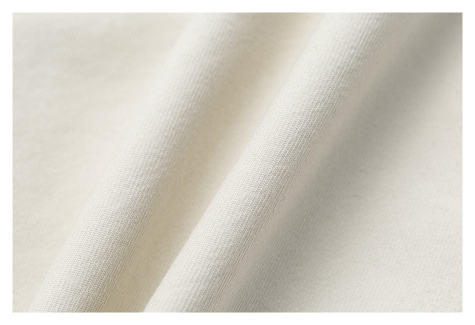 Close-up of light ivory fabric showing its fine woven texture and soft folds.