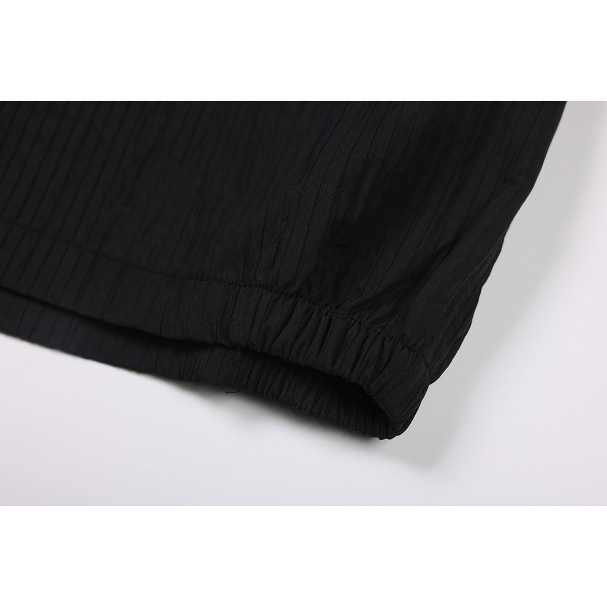 Close-up of black shorts showing the gathered elastic leg opening and textured fabric.