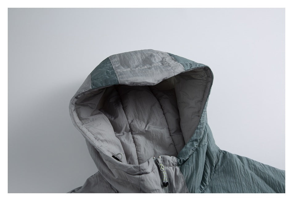 Close-up of the jacket's padded hood, showing gray lining, teal outer panels, and adjustable cords at the neck.