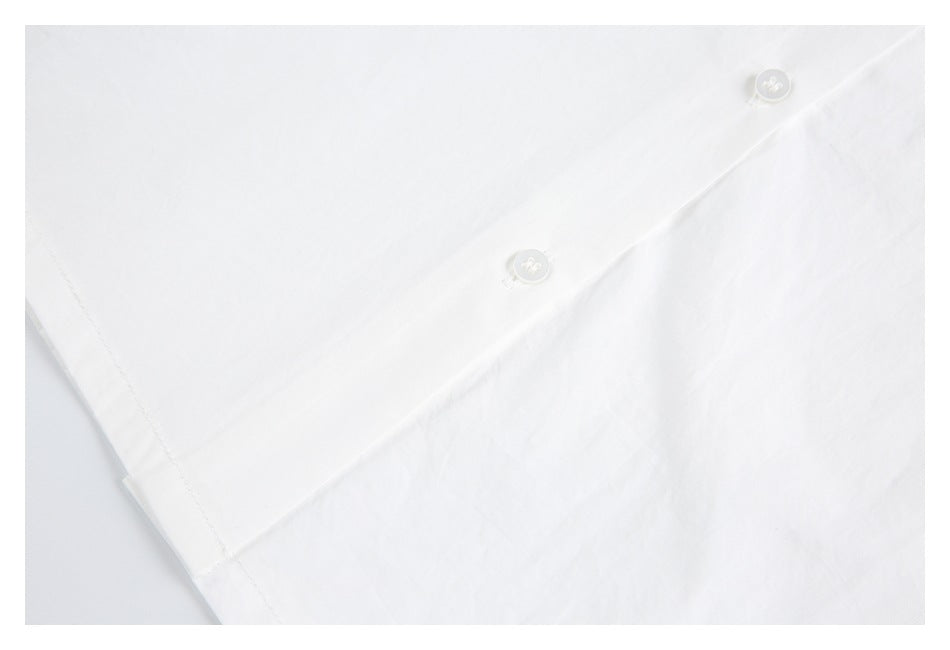 Close-up of a white garment panel with two white buttons and a visible side seam.