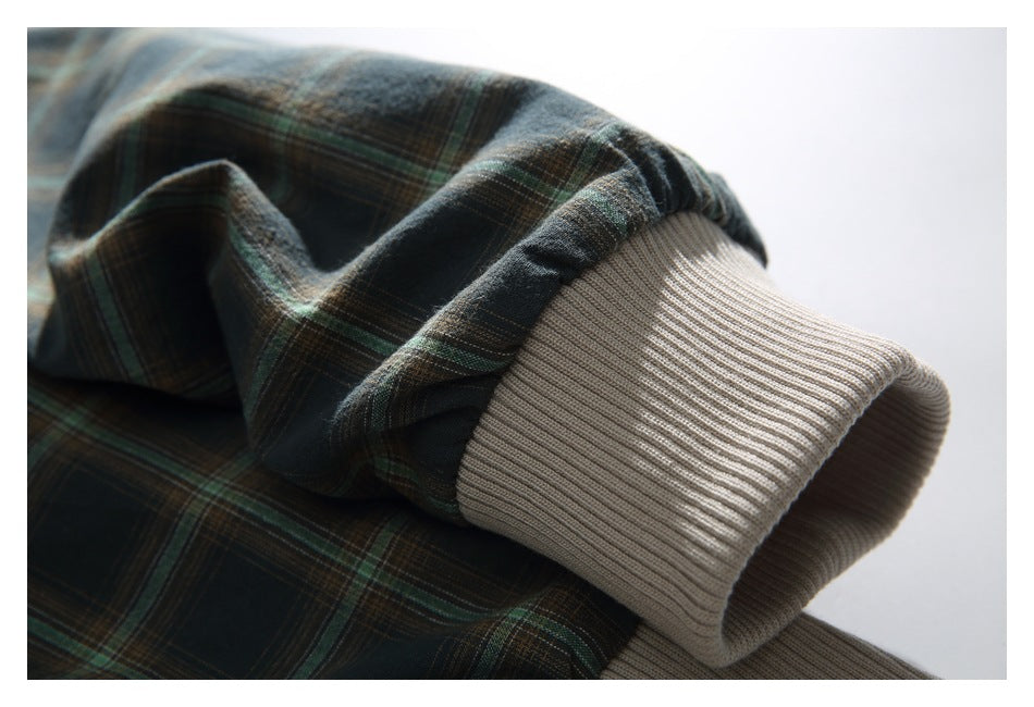 Close-up of a plaid sleeve ending in a wide beige rib-knit cuff.
