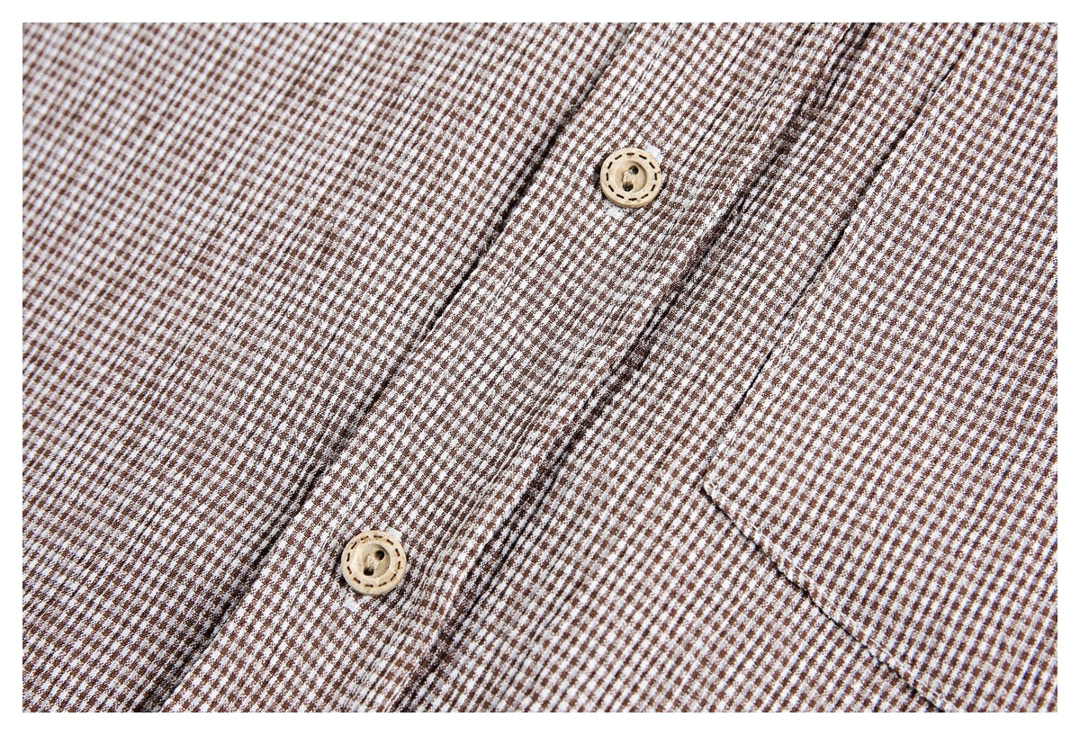 Detailed view of the brown-and-white checked shirt's buttons, placket stitching, and pocket edge.