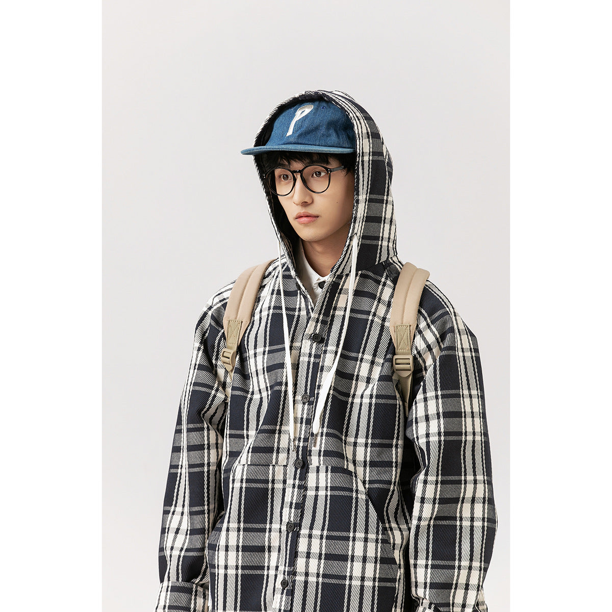 Front close-up of a model wearing a black-and-white plaid button-front hooded jacket.