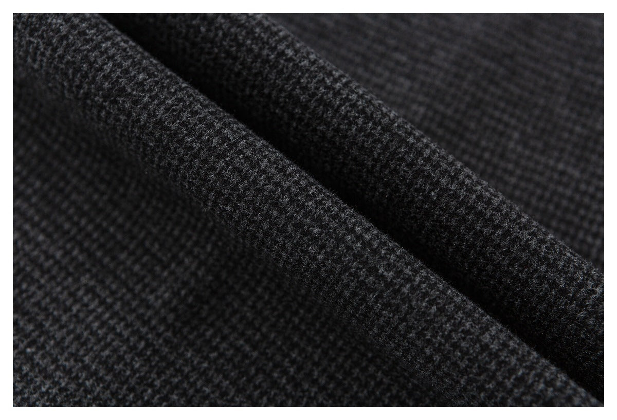 Macro view of the dark charcoal and gray patterned trouser fabric folded into a ridge.