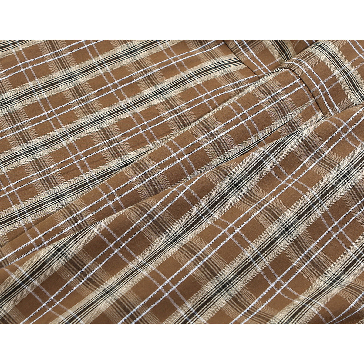 Close-up of the brown shirt's plaid pattern, with intersecting white, black, and tan lines.