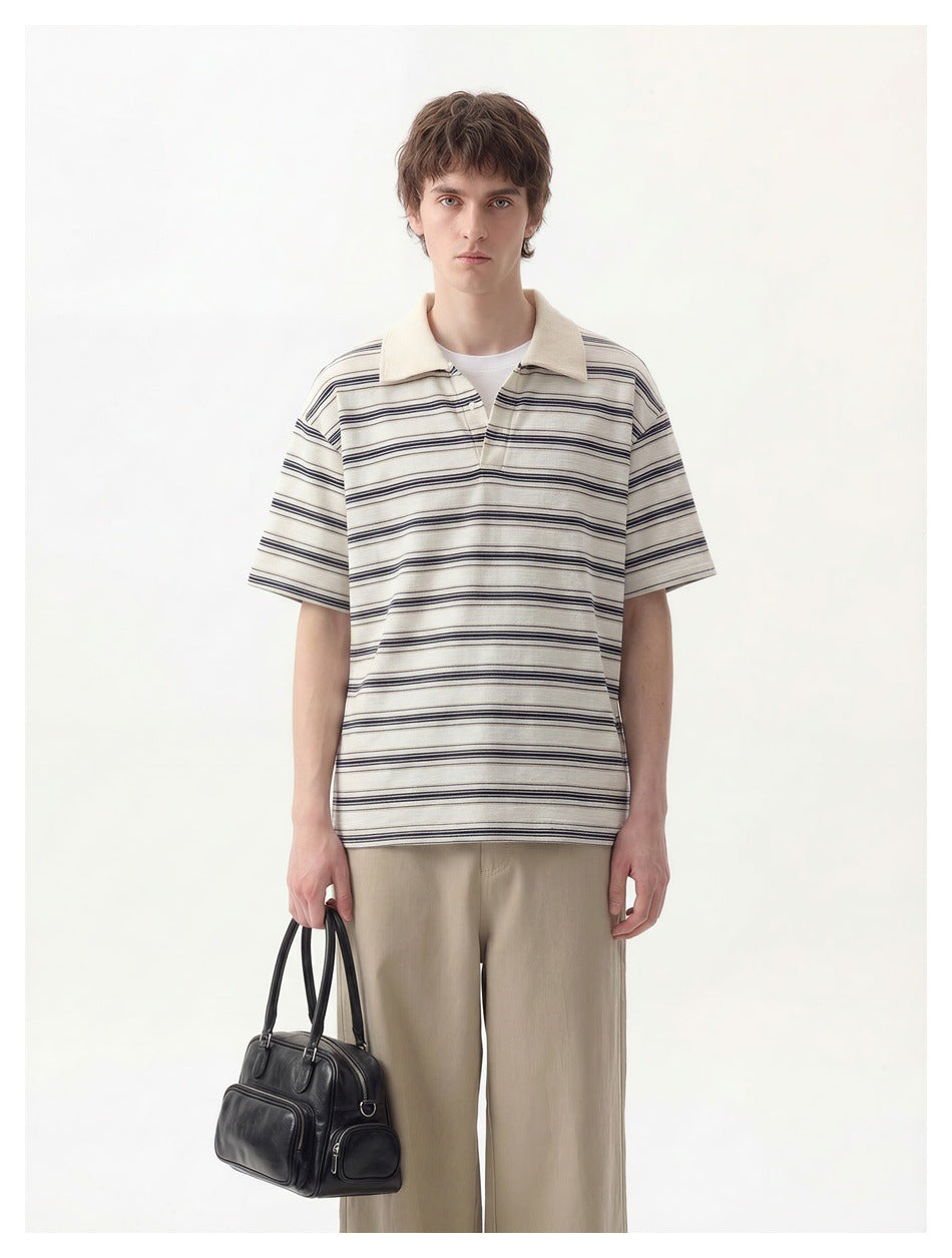 Man wearing an ivory polo with navy horizontal stripes, a cream collar and short sleeves.