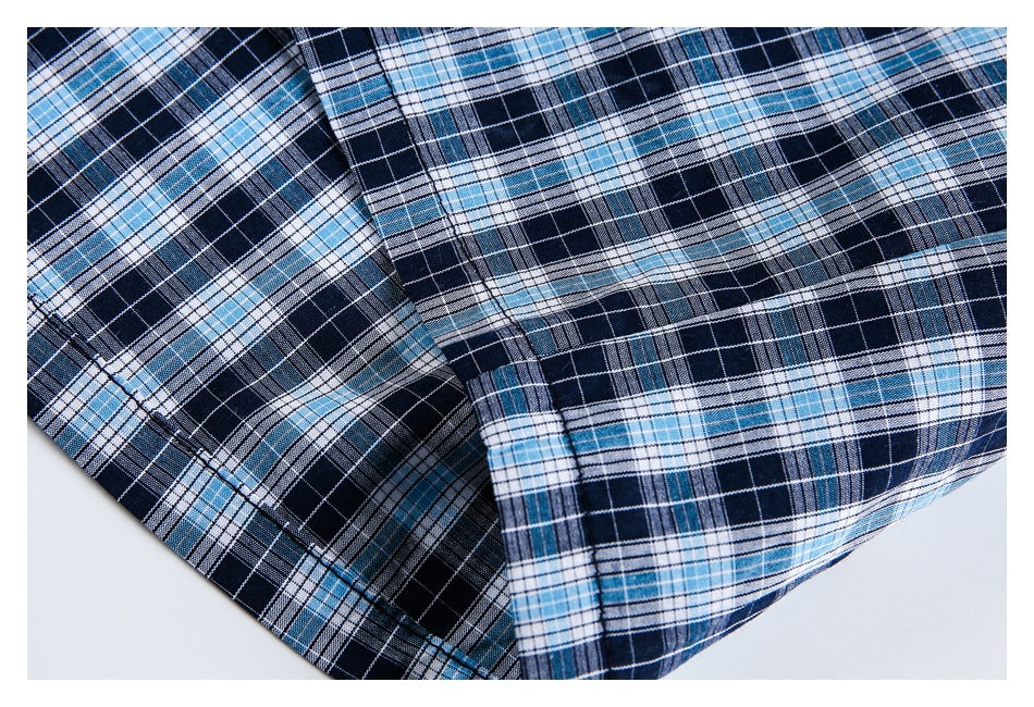 Close-up of the plaid shirt's hem and intersecting seams in navy, light blue, and white.