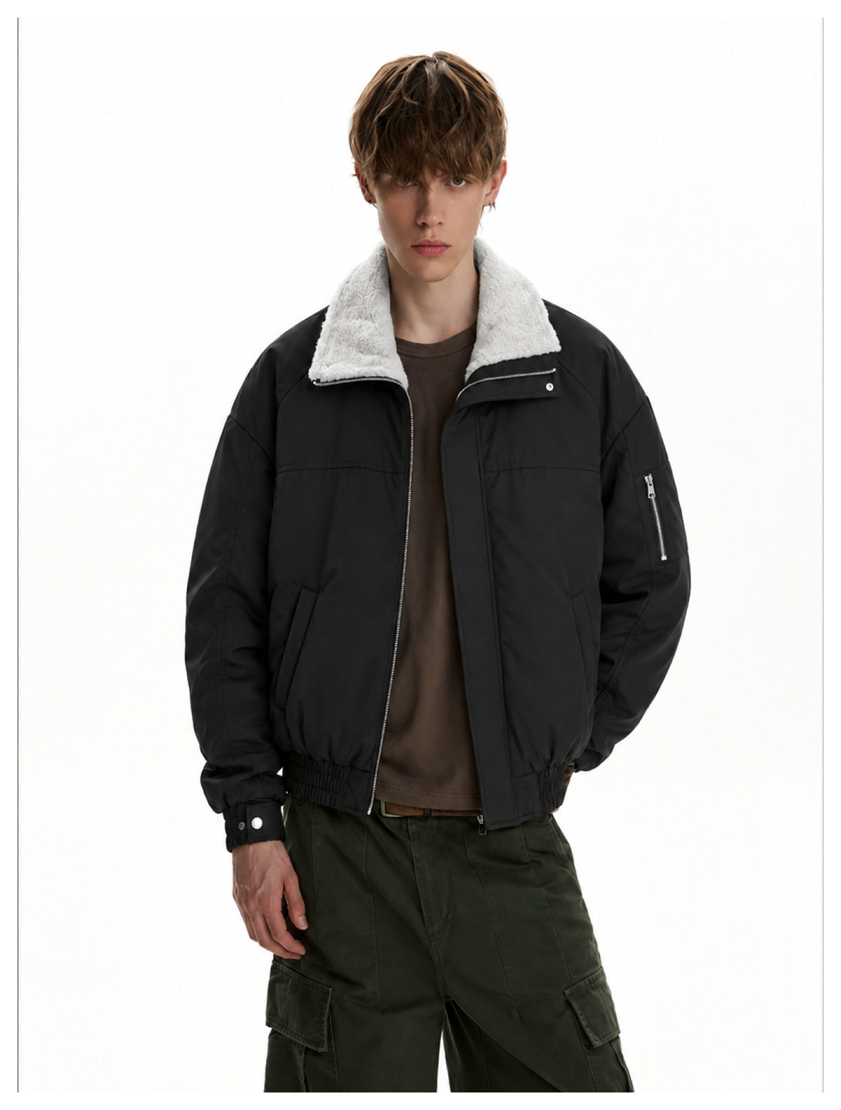 Front view of a model wearing a black jacket with a white fleece collar, zip sleeve pocket and olive cargo pants.