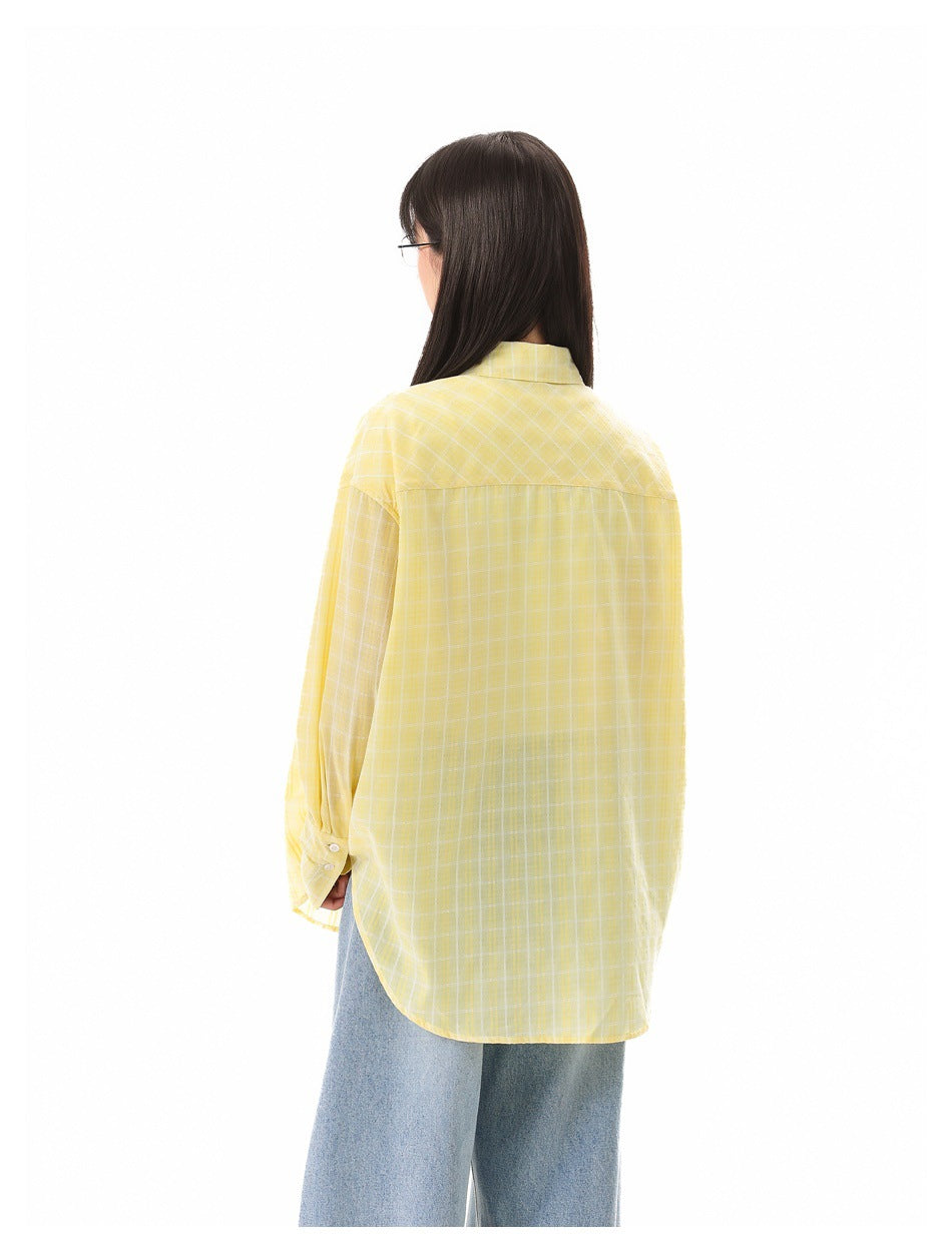 Back view of a model wearing an oversized yellow-and-white plaid button-up shirt with wide-leg blue jeans.