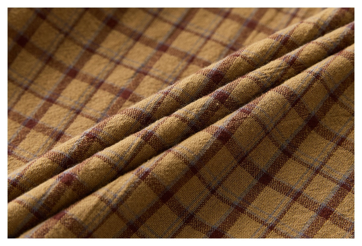Macro view of the textured mustard-brown plaid fabric, draped in folds.