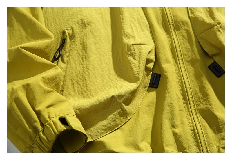 Close-up of the yellow jacket front with zip pockets, black zipper pulls, center zipper, and an adjustable cuff.